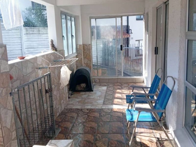 A covered patio area featuring tiled flooring, wall cladding, and sliding glass door access to the main living space.