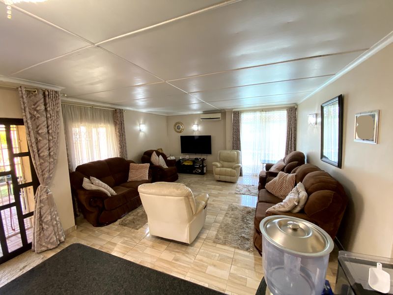 Spacious living room featuring tiled flooring, a wall-mounted air conditioning unit, and sliding glass doors providing access to the exterior.