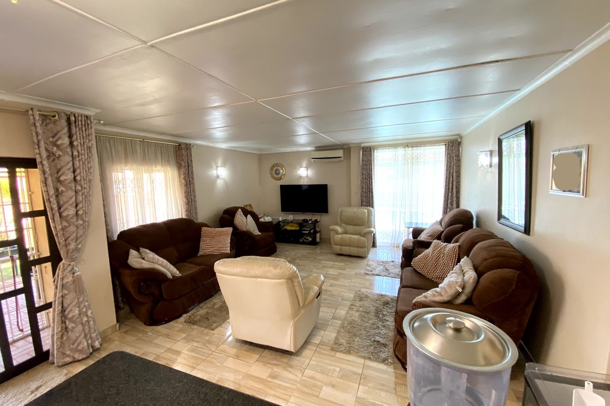 Spacious living room featuring tiled flooring, a wall-mounted air conditioning unit, and sliding glass doors providing access to the exterior.