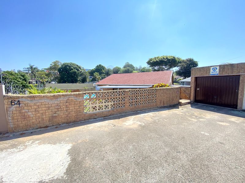 Front exterior view of the property featuring a brick boundary wall with decorative breeze blocks, a garage, and a tiled roof.