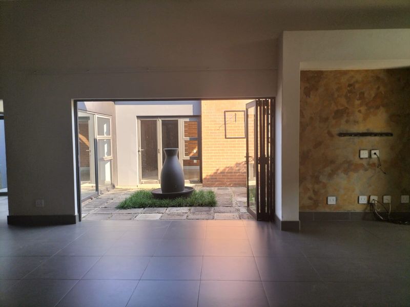Spacious living area with large bi-fold doors opening onto a private courtyard, featuring tiled floors and a textured accent wall.