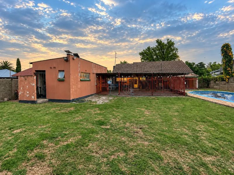 Rear view of the property featuring a swimming pool, a covered patio area, and a spacious garden with a detached structure.