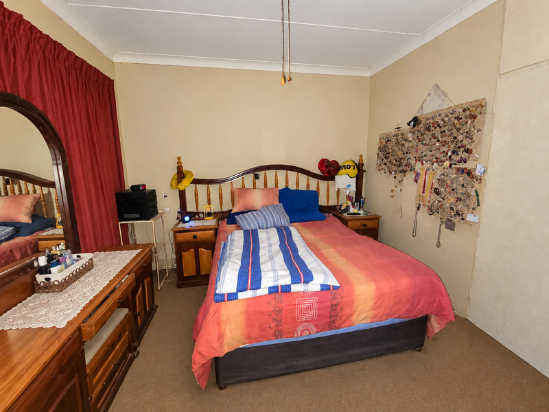 A standard bedroom featuring carpeted flooring, a built-in cupboard, and coved ceiling details, offering a functional space ready for modernization.