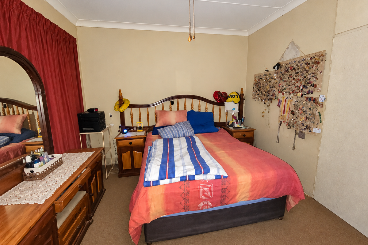 A standard bedroom featuring carpeted flooring, a built-in cupboard, and coved ceiling details, offering a functional space ready for modernization.