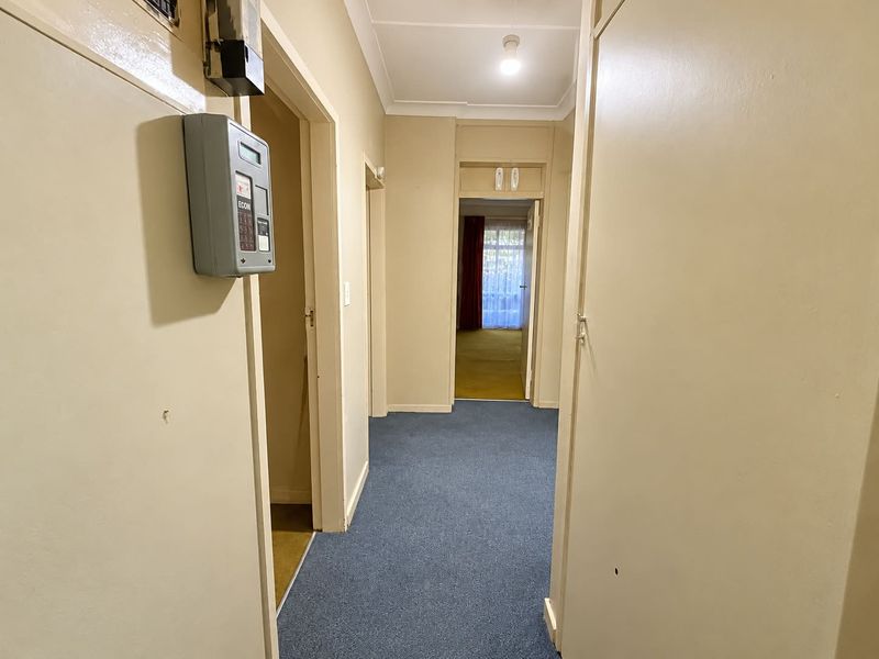 A functional hallway featuring built-in storage cupboards and a wall-mounted prepaid electricity meter, providing access to adjacent rooms.