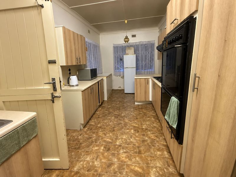 A functional kitchen featuring light wood-look cabinetry, built-in double oven, and vinyl flooring, requiring some cosmetic updates to the wall finishes.