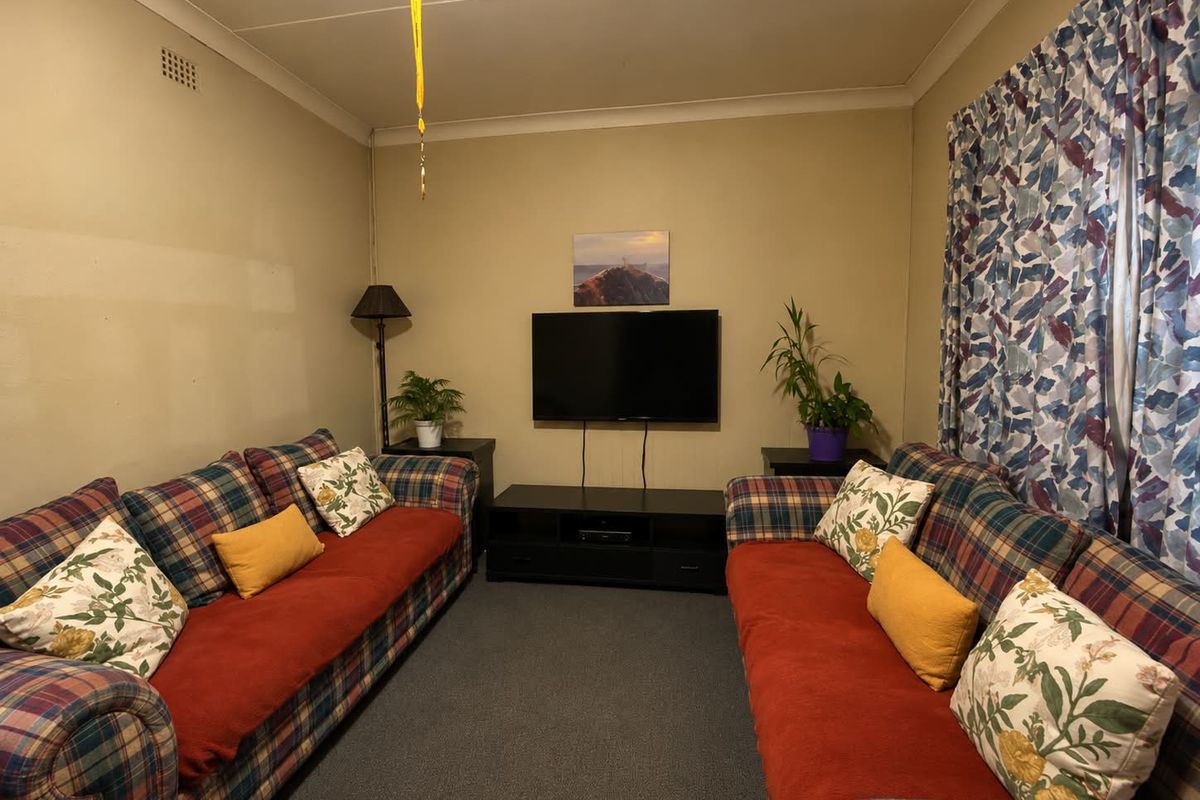 A compact living room featuring carpeted flooring and coving, currently requiring cosmetic updates to the wall finishes.