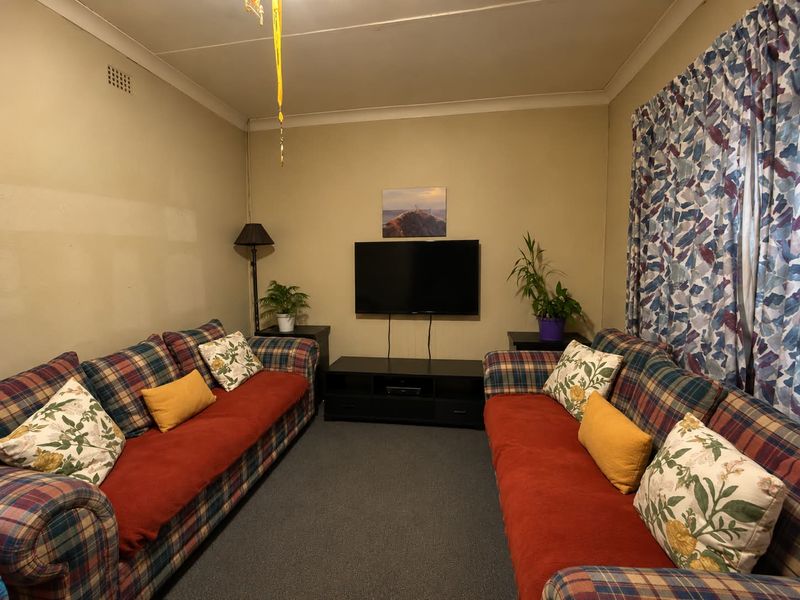 A compact living room featuring carpeted flooring and coving, currently requiring cosmetic updates to the wall finishes.