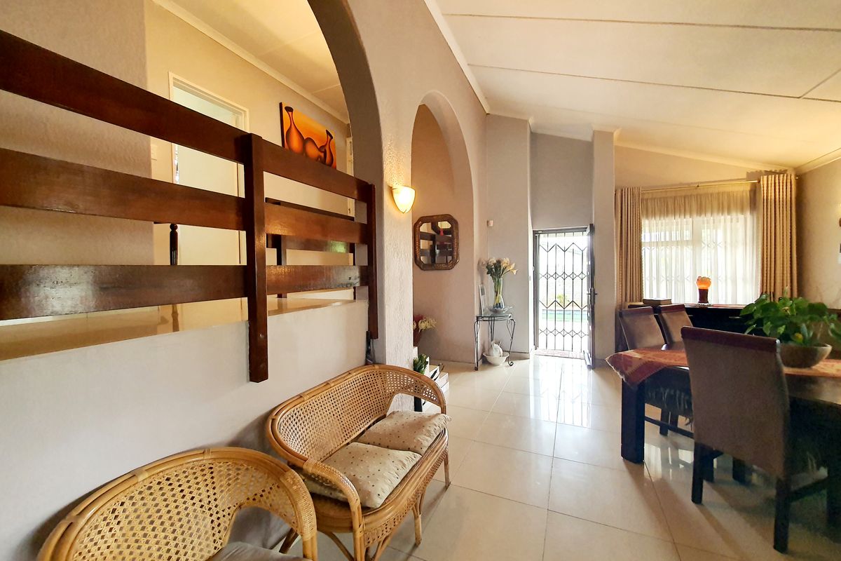 Spacious living area featuring arched architectural details, tiled flooring, and a secure entrance door leading to the exterior.
