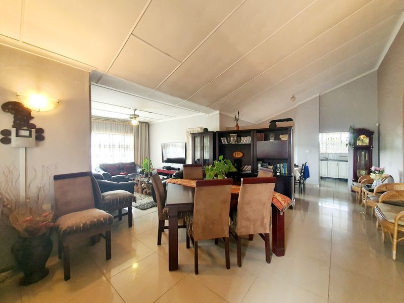 Spacious open-plan living and dining area featuring vaulted ceilings, tiled flooring, and a seamless flow into the adjacent kitchen space.