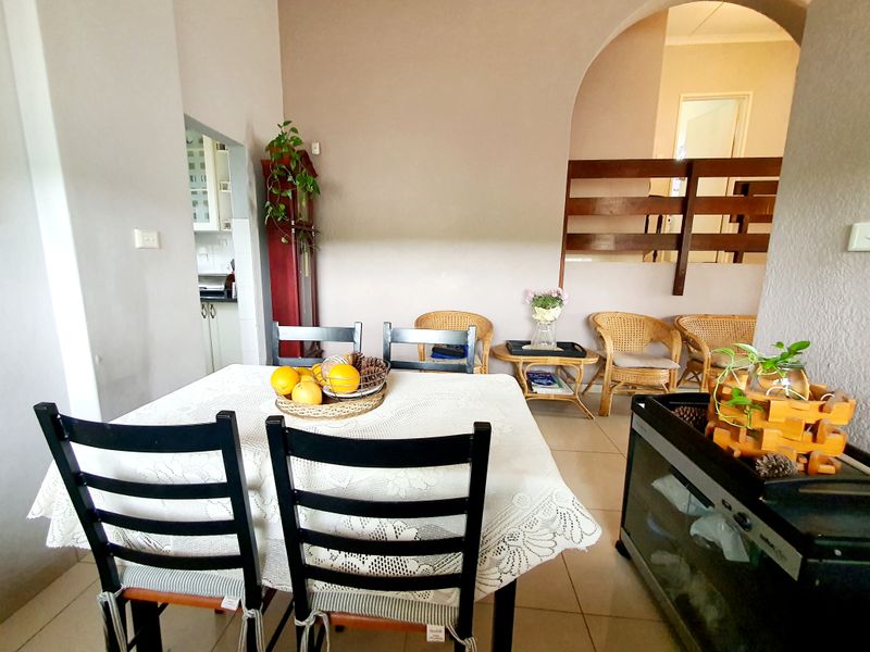 A dining area featuring tiled flooring, an arched architectural opening, and a timber room divider leading to an adjacent space.