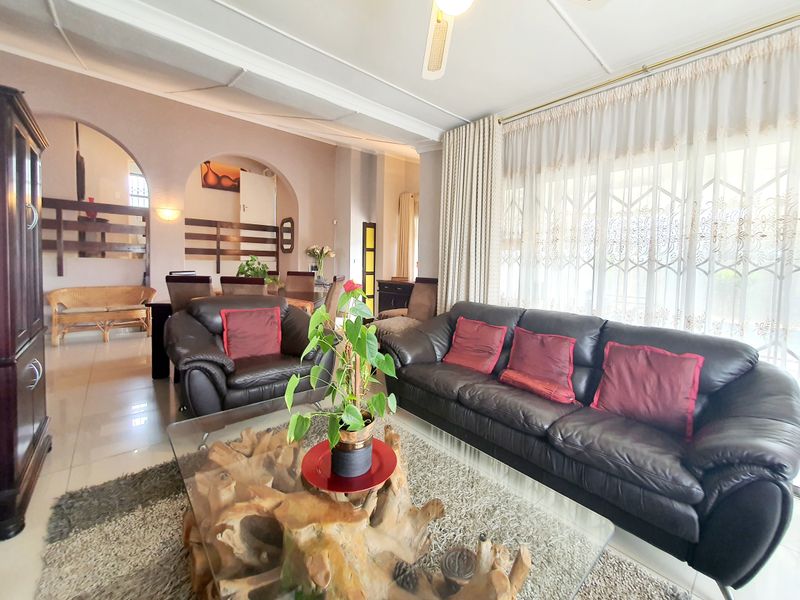 Spacious open-plan living and dining area featuring tiled flooring, decorative archways, and a ceiling fan, offering a bright and functional layout.