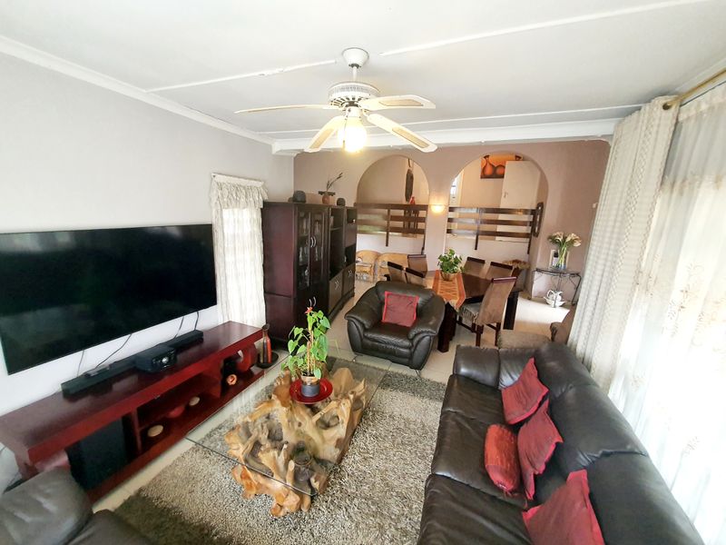 Open plan living and dining area featuring tiled flooring, a ceiling fan, and decorative archways connecting the spaces.
