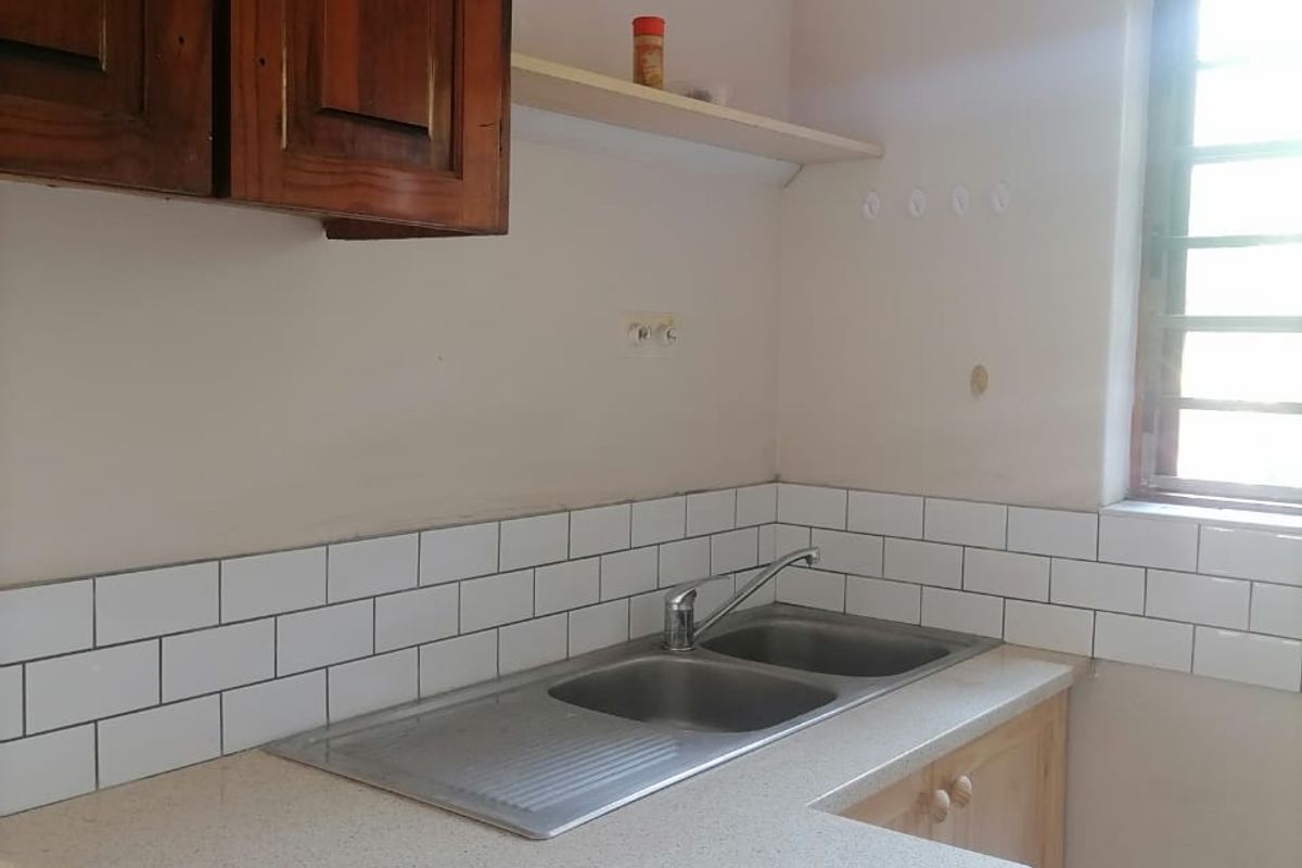 A functional kitchen area featuring a double bowl stainless steel sink, subway tile backsplash, and a mix of wooden cabinetry and laminate countertops.