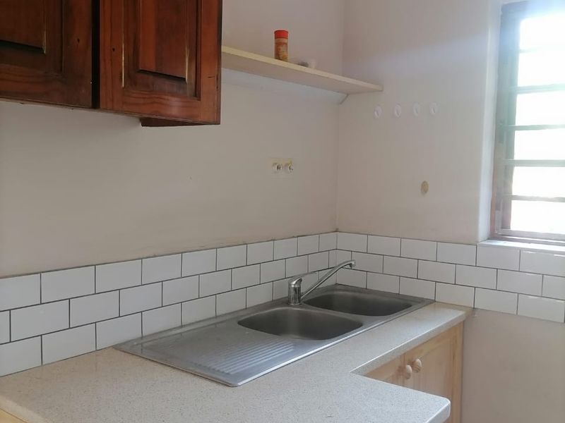 A functional kitchen area featuring a double bowl stainless steel sink, subway tile backsplash, and a mix of wooden cabinetry and laminate countertops.