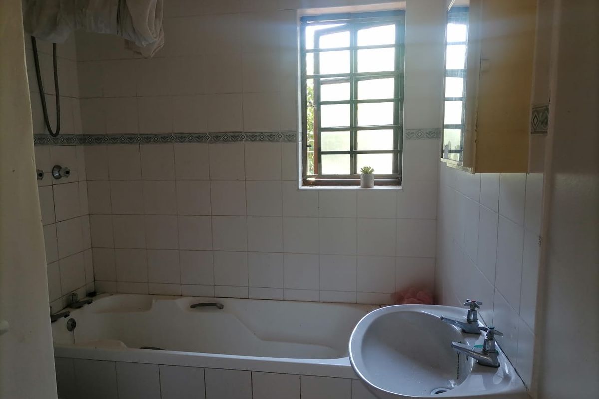A dated bathroom featuring a standard bathtub, pedestal basin, and tiled walls, requiring modernization to improve its aesthetic and functional appeal.