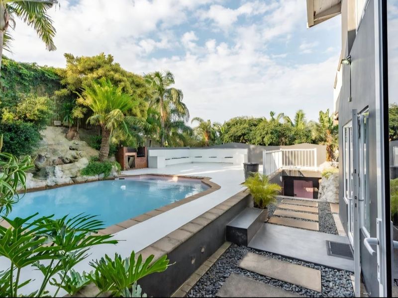 Outdoor pool area featuring a swimming pool, built-in braai, and landscaped rockery, providing a well-maintained space for outdoor entertainment.