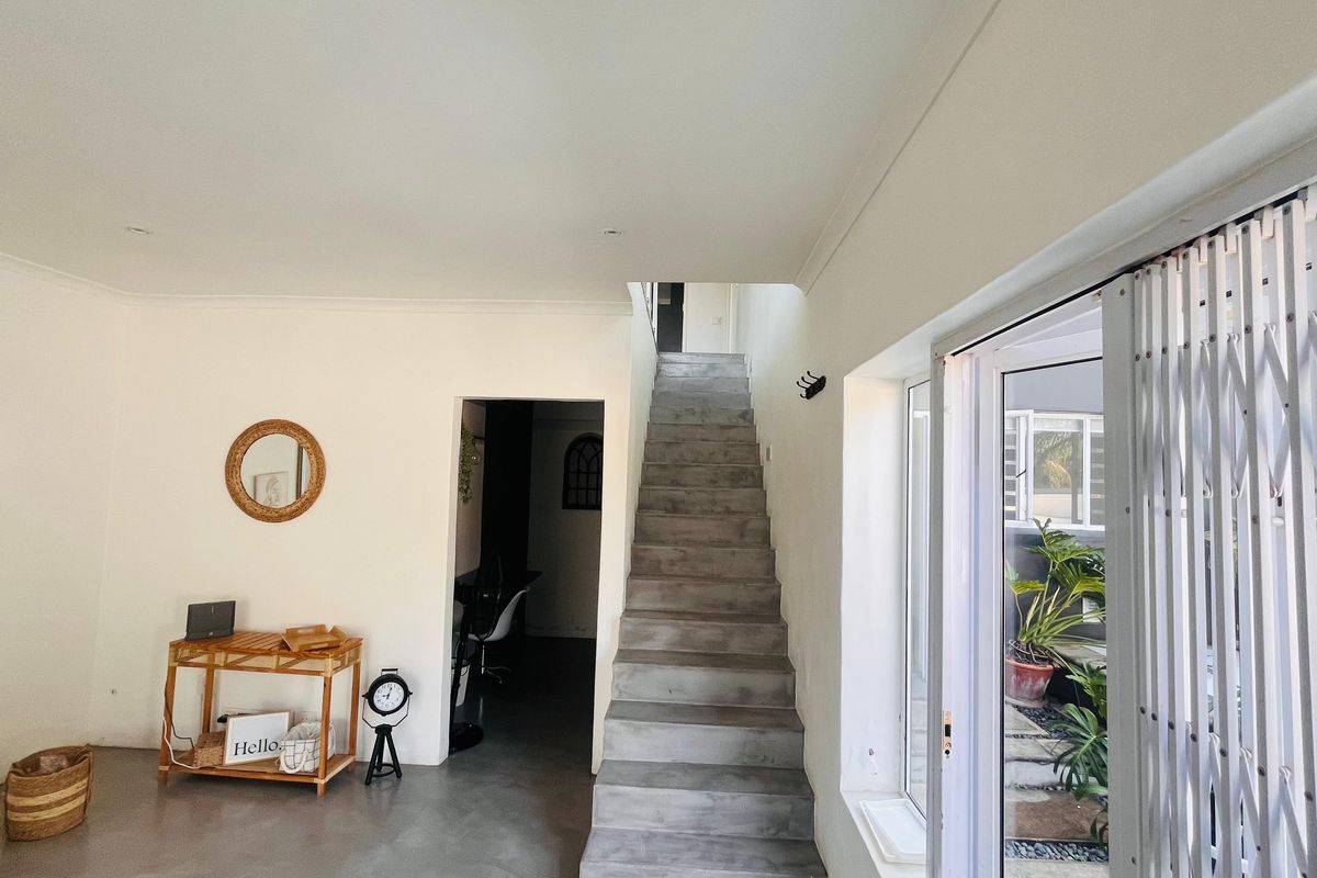 Open plan living area featuring polished concrete flooring, a modern concrete staircase, and large sliding glass doors leading to an outdoor space.