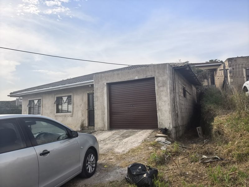 Front exterior view of a house featuring a roller garage door, unrendered concrete block walls, and a concrete driveway in need of maintenance.