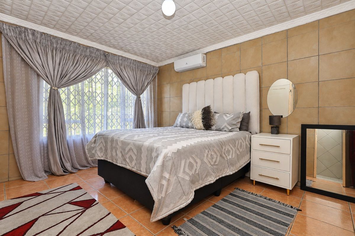 A bedroom featuring tiled walls and flooring, a textured ceiling, and a wall-mounted air conditioning unit.