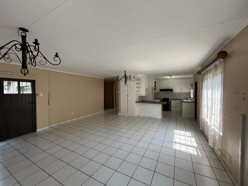 Spacious open-plan living and kitchen area featuring tiled flooring, built-in cabinetry, and classic wrought iron chandeliers, offering a versatile layout for modern living.