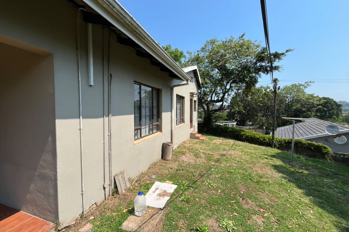 A view of the rear exterior of the house, featuring a lawn area, guttering, and aluminium window frames.