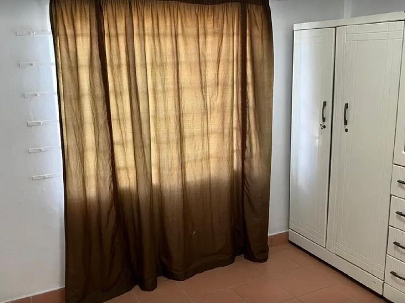 A bedroom featuring tiled flooring, a built-in wardrobe, and a window fitted with security bars.
