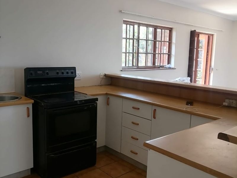 A functional kitchen featuring white cabinetry, laminate countertops, a breakfast bar, and tiled flooring, offering a clean canvas for potential modern updates.