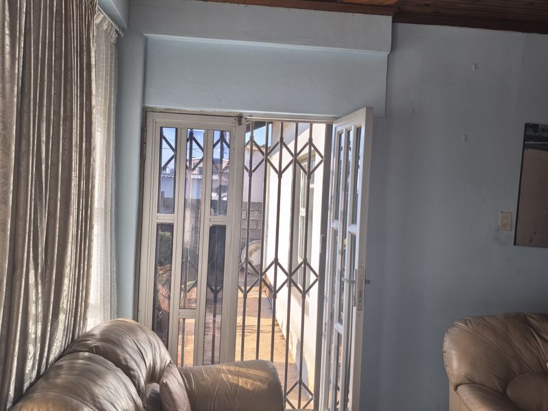 Living room featuring parquet flooring and a timber tongue and groove ceiling, with direct access to an outdoor area through a security gate.