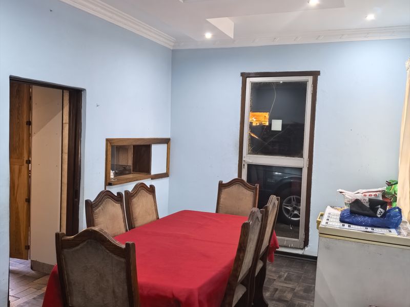 Dining room featuring parquet flooring, recessed ceiling with cove molding, and an internal window, offering a functional space for family meals.