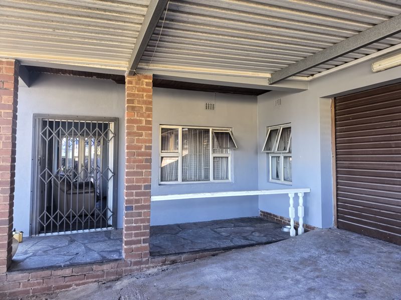 A covered patio area featuring stone flooring, brick support pillars, and secure access points, providing a functional outdoor space.