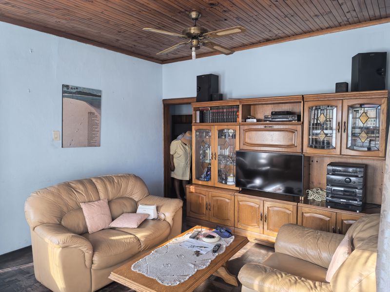A living room featuring a timber-paneled ceiling, a ceiling fan, and extensive built-in wooden cabinetry providing ample storage and display space.