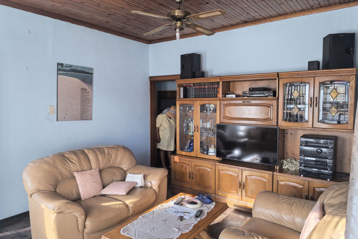 A living room featuring a timber-paneled ceiling, a ceiling fan, and extensive built-in wooden cabinetry providing ample storage and display space.