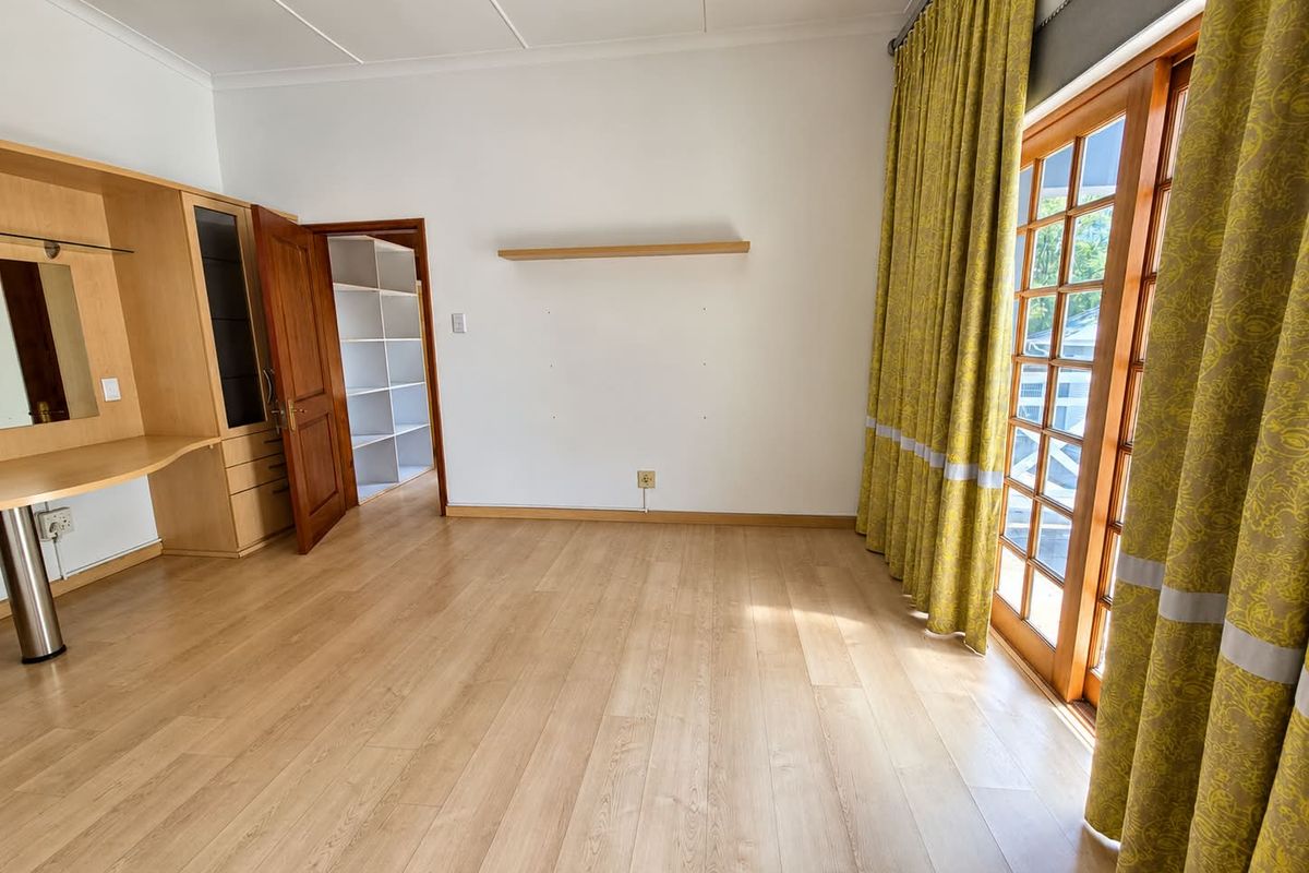 Spacious bedroom featuring light laminate flooring, built-in vanity, walk-in closet, and wooden french doors leading to the exterior.
