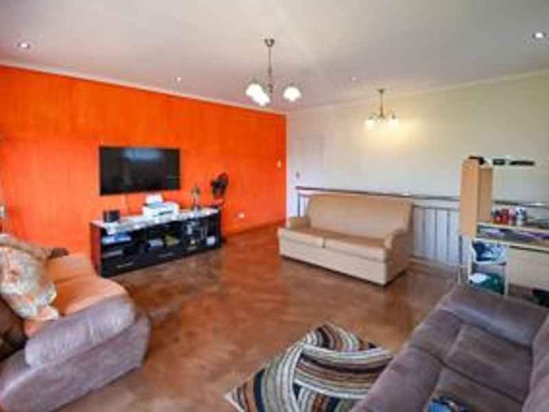Spacious living room featuring tiled flooring, recessed downlighting, and a prominent accent wall, offering a versatile layout for comfortable family living.