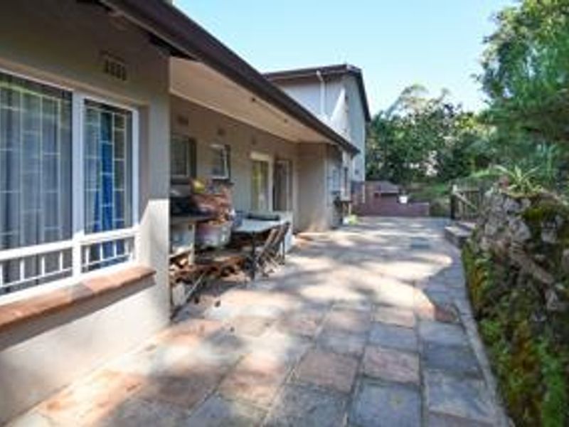 A paved outdoor patio area featuring a stone retaining wall and direct access to the home's exterior, offering a functional space for outdoor living.