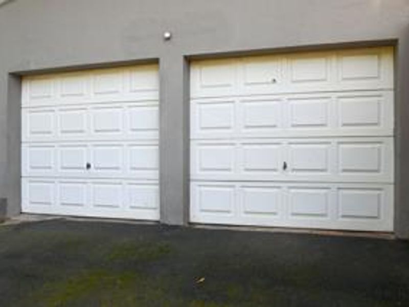 A double garage featuring white sectional doors and an asphalt driveway.
