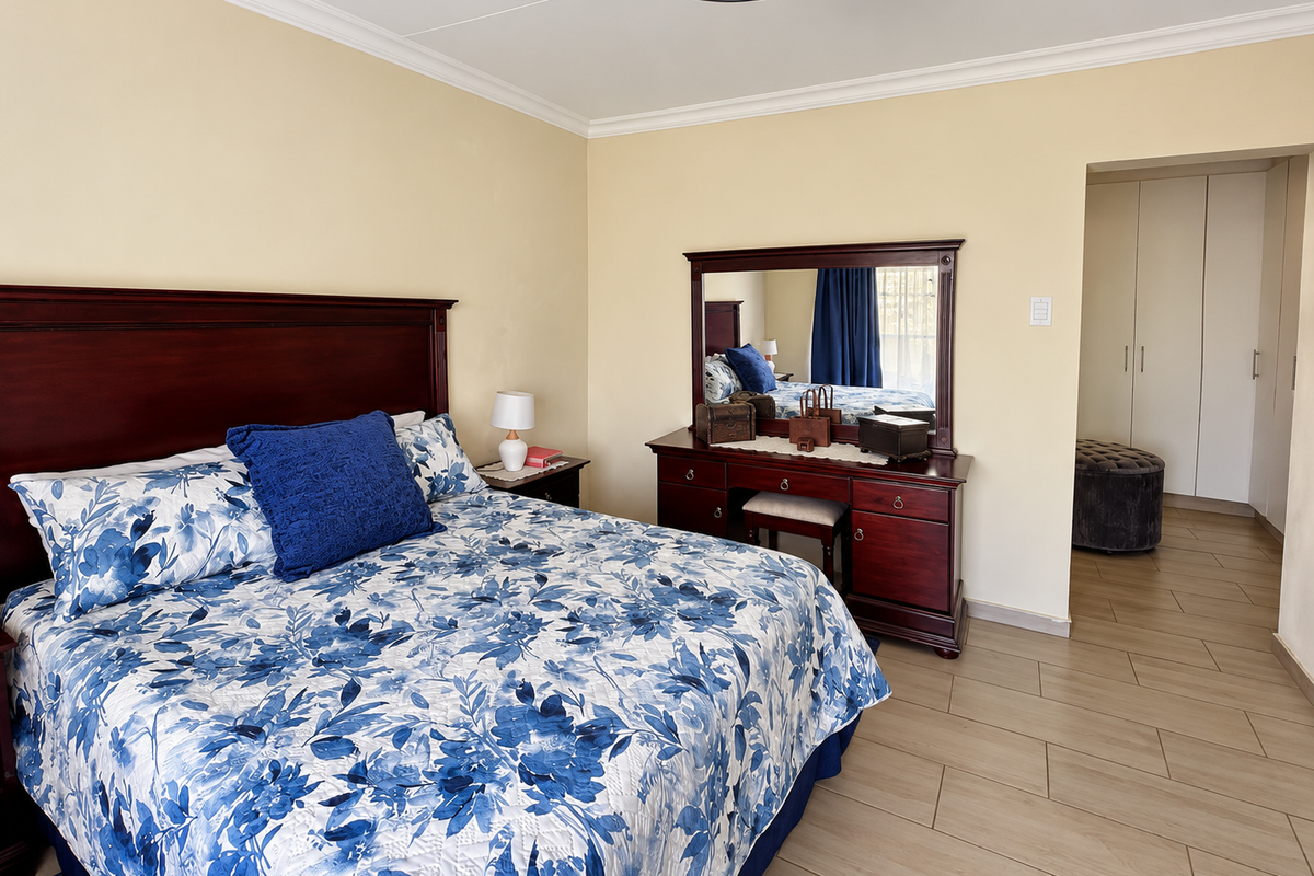 A well-maintained bedroom featuring tiled flooring, built-in cupboards, and classic ceiling cornicing, offering a clean and functional living space.