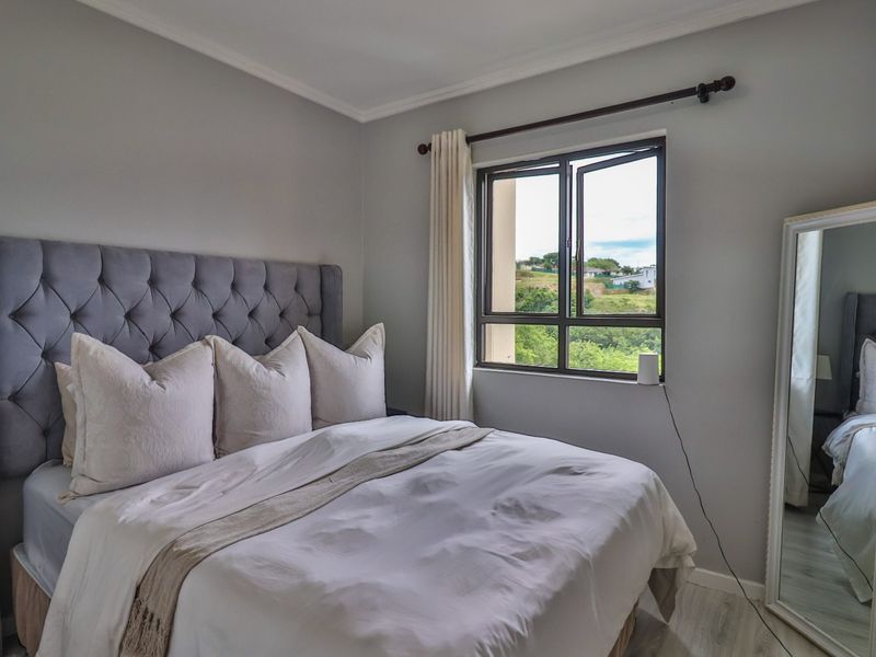 A well-maintained bedroom featuring neutral wall tones, a casement window with natural light, and classic coving detail.