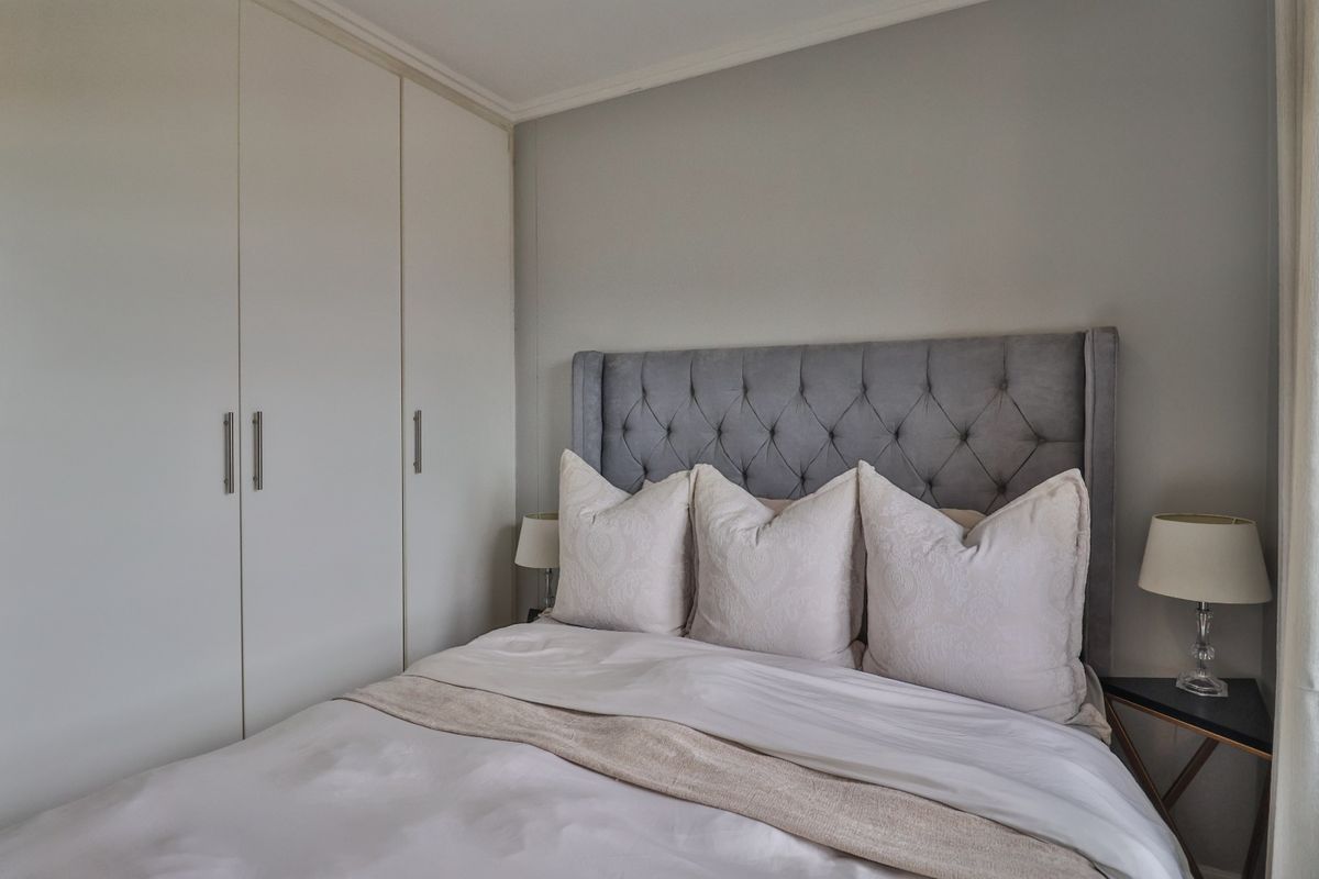 A well-maintained bedroom featuring neutral wall tones and practical floor-to-ceiling built-in cupboards for ample storage.