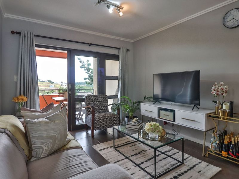 A comfortable living room featuring tiled flooring and a large sliding glass door that provides access to an outdoor balcony area.