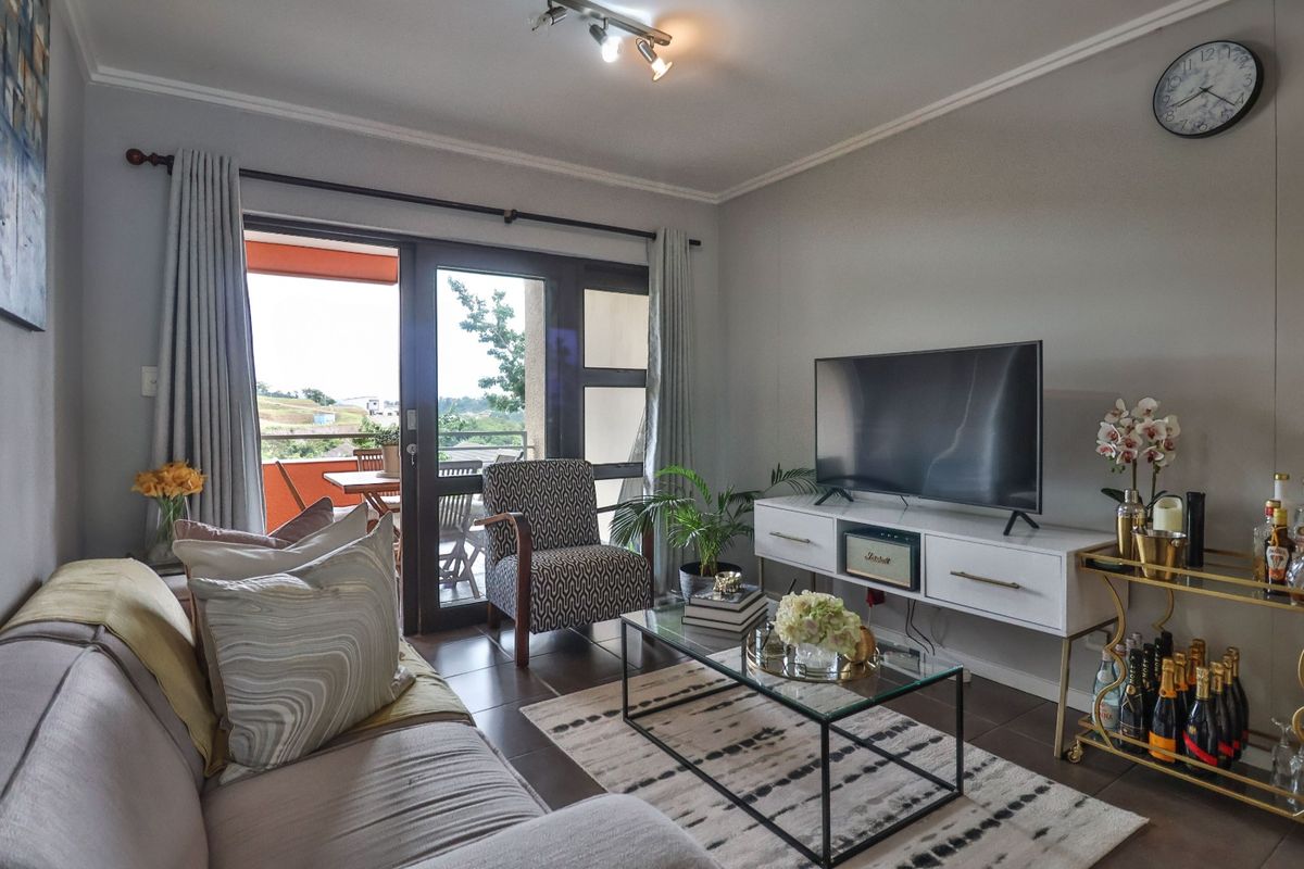 A comfortable living room featuring tiled flooring and a large sliding glass door that provides access to an outdoor balcony area.