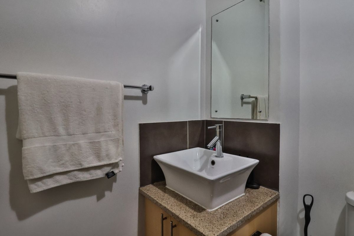 A compact bathroom vanity featuring a modern vessel sink, granite countertop, and a wall-mounted mirror with a tiled splashback.