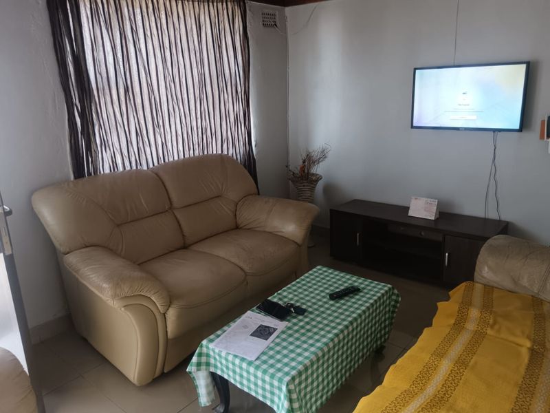A living room area featuring tiled flooring and wall-mounted television infrastructure, requiring cosmetic updates to improve the overall condition of the space.