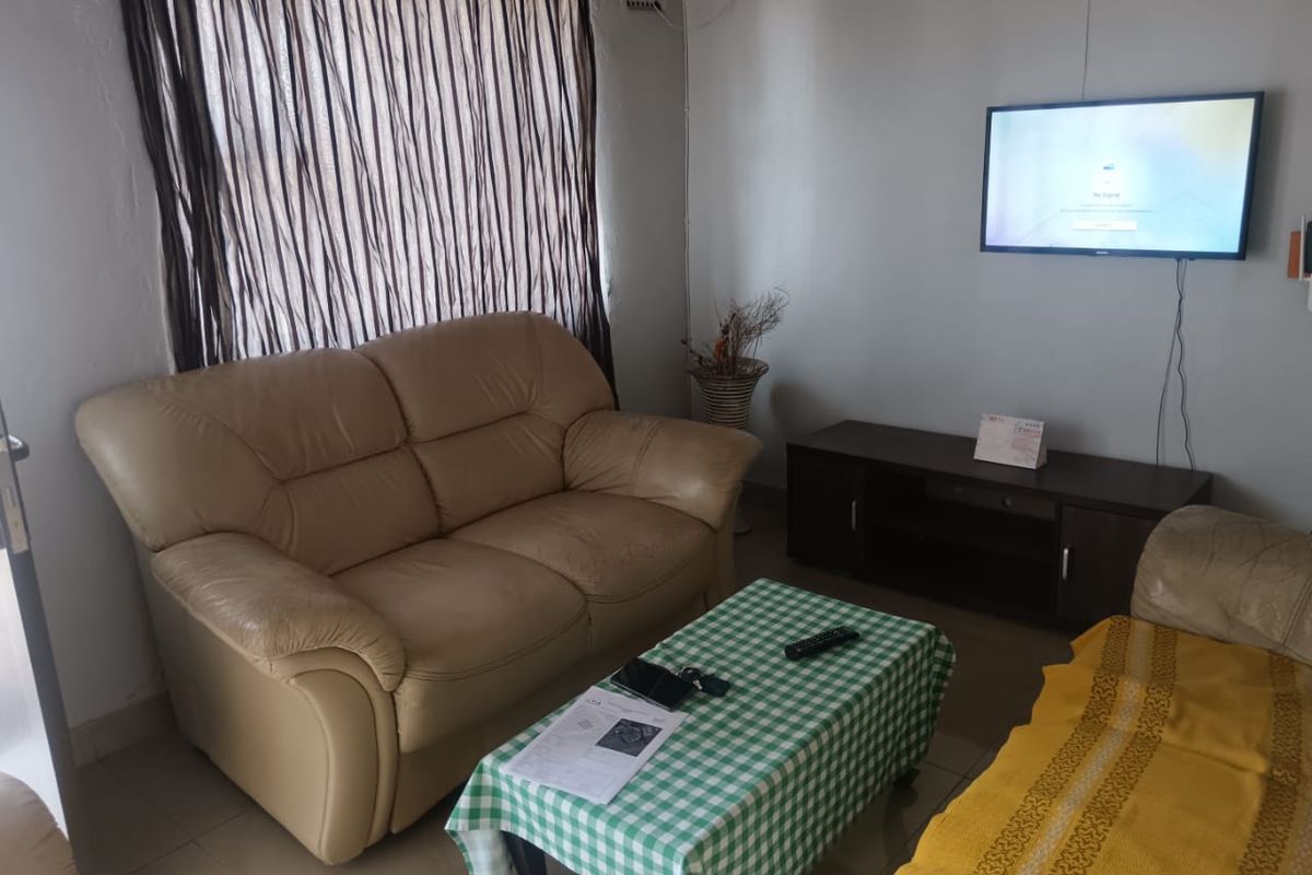 A living room area featuring tiled flooring and wall-mounted television infrastructure, requiring cosmetic updates to improve the overall condition of the space.