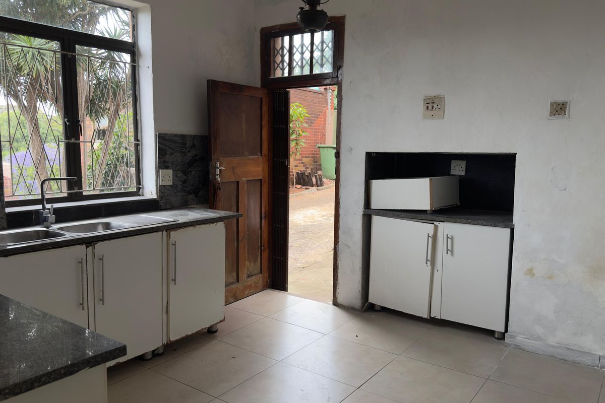 A dated kitchen featuring granite countertops, built-in cabinetry, and tiled flooring, requiring cosmetic updates and wall repairs to improve its overall condition.