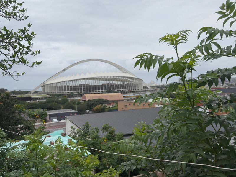 An elevated view overlooking the surrounding neighbourhood and the prominent Moses Mabhida Stadium arch in the distance.