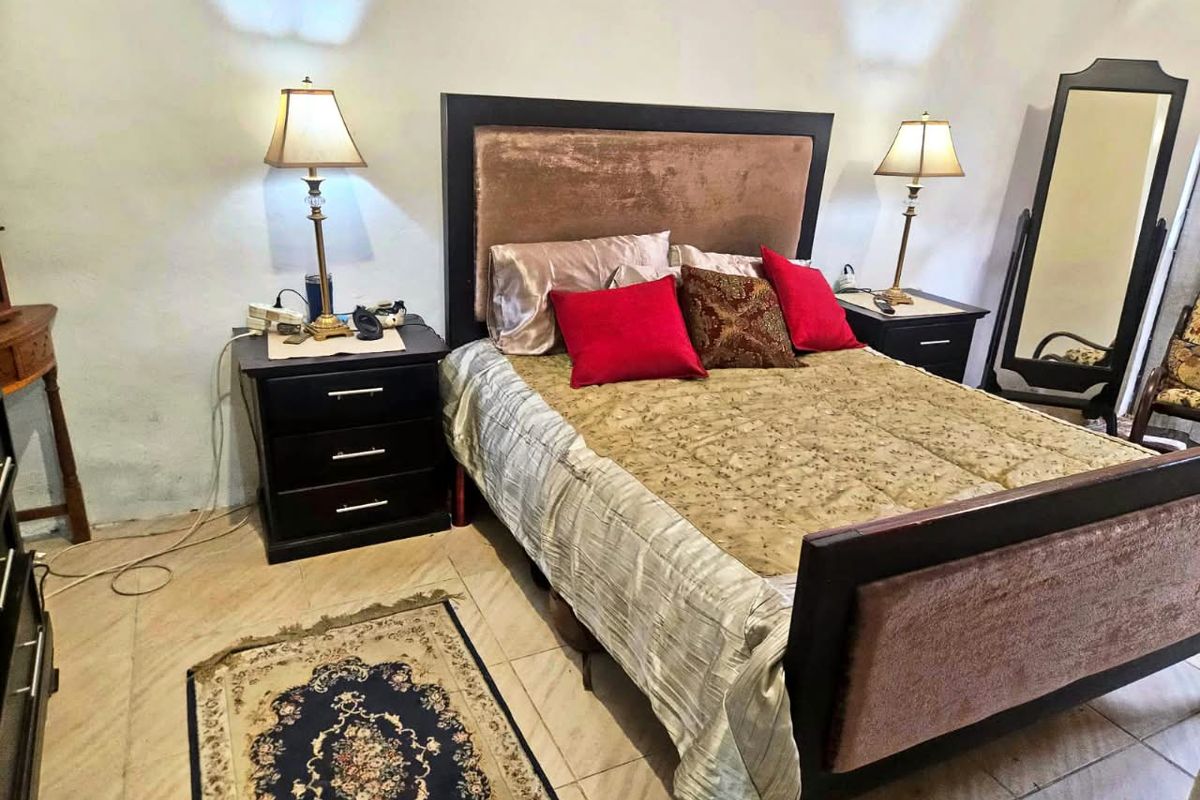 A bedroom featuring tiled flooring and neutral wall finishes, currently furnished with a bed and bedside tables.