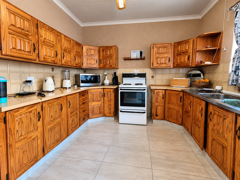 A functional kitchen featuring traditional wooden cabinetry, tiled backsplash, and a freestanding stove, offering a classic layout with ample storage space.