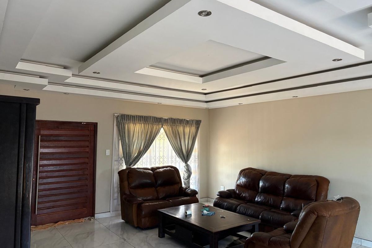 Spacious living room featuring a modern recessed ceiling with integrated downlights and polished tiled flooring.
